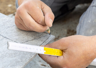 Carpenter drawing line over tile to cut before tiling, hands closeup. Construction or  Home...