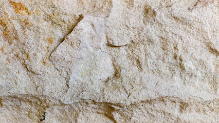 Close-up of a rugged natural stone surface, showcasing its weathered texture and earthy appeal, perfect for backgrounds and architectural design elements