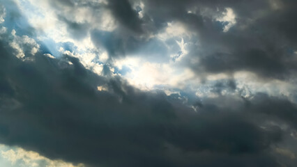 Beams of sunlight bursting from behind dark, foreboding clouds, symbolizing hope and divine light