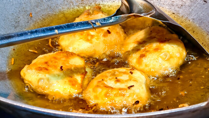 The deliciousness of fried golden crispy fermented cassava in a frying pan filled with bubbling hot oil is a culinary temptation