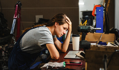 Worried woman entrepreneur in car service shop having business difficulties