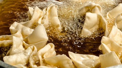 Golden deep frying process transforms dough into crispy won tons for an Asian snack delight