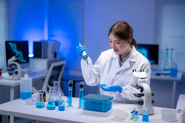 Scientist dropping blue liquid on a petri dish using a micropipette in a laboratory