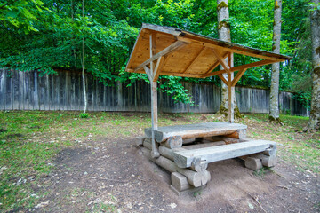 recreation area in a forest, gazebo with a bench and table in the middle of a forest in a clearing