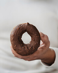 Hand holding chocolate glazed donut close up