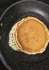 Vista de cerca de pancake casero cocinándose en sartén para desayunar