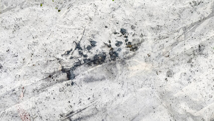 Abstract image of a textured white surface with dark, irregular stains and subtle creases or folds.