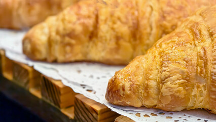Warm, crispy golden croissants on a wooden display tempt bakery visitors to take a bite