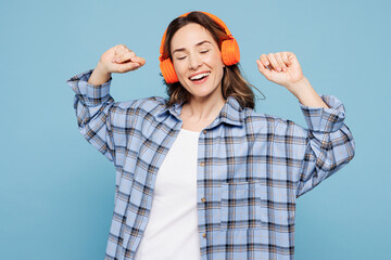 Young smiling woman she wears checkered shirt casual clothes listen to music in headphones raise up...