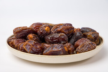 Dates fruit in a bowl on white background. Selective focus.