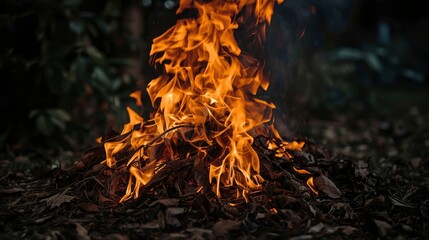 Bonfire with orange flames burning leaves