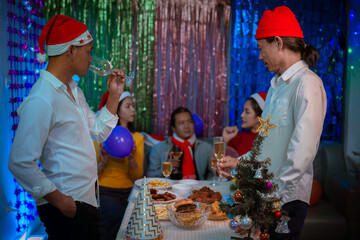 Happy friends celebrating Christmas at home Friends gather at home for a traditional Christmas dinner, young couples enjoying the festive food.
