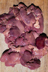 Freshly prepared chicken liver displayed on a wooden cutting board, showcasing vibrant colors and textures for culinary purposes