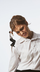 Modern collage. Tiny man climbing woman hair as she reacts in discomfort. Concept of gender...