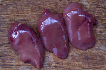 Fresh chicken liver prepared for cooking on a rustic kitchen table on a sunny day