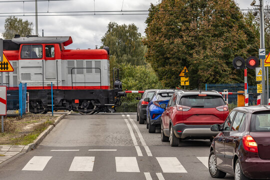 Cars waiting at a railway crossing with a passing freight train