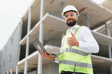 Construction engineer giving thumbs up holding laptop