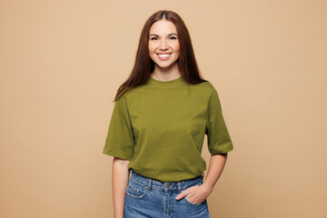 Young smiling happy cheerful satisfied woman she wearing olive green t-shirt casual clothes look camera isolated on plain pastel light beige color wall background studio portrait. Lifestyle concept