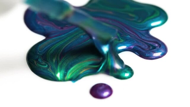Swirled teal and purple nail polish droplet on white surface