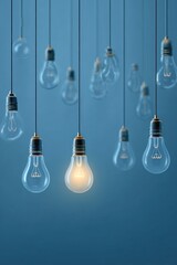 Lightbulbs hanging against a blue background, one glowing, signifying an idea