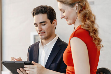 hotel receptionist assists a guest using a digital tablet during check-in, providing professional customer service and hospitality in a modern hotel environment with a friendly atmosphere.