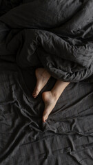 Naklejka premium fragile female legs in bed under a gray blanket