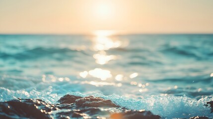 Sunlight reflects on gentle ocean waves crashing against rocks at dawn.