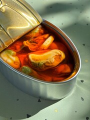 Open can of mussels in brine on green background
