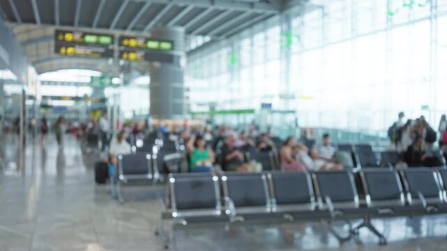 Blurred view of people waiting in an airport terminal with defocused backgrounds and bokeh lighting that highlights a travel-focused environment.
