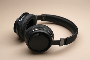 Picture of sleek contemporary black headphones on a light tan backdrop