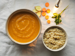A top down view of a healthy and delicious bowl of vibrant orange carrot soup served with a side of fluffy quinoa and fresh ingredients