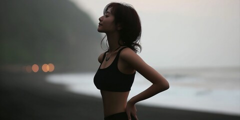 Asian young female standing on beach at dusk in athletic wear