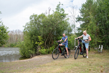 Family couple enjoying an active summer day cycling electric bicycles through a peaceful forest...