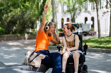 Senior woman and young friend enjoying music outdoors