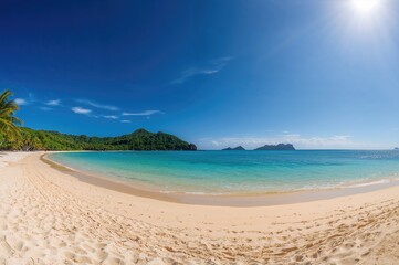 Fototapeta premium Wide-angle view of a sunny tropical shoreline with white sand