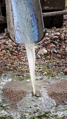 Water flows down the chute of a concrete mixer. Washes the concrete mixer after use. Washing away the remaining cement mixture. Cleaning of special vehicles. Dirty water. Construction site. Vertical.
