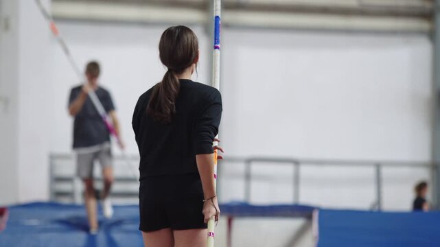 Female athlete practicing pole vaulting indoors