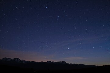Naklejka premium Star trails over mountain landscape during nighttime