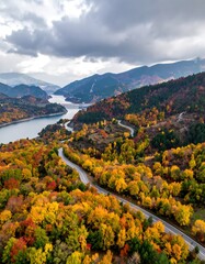 Autumnal mountain road winding by lake
