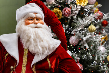 Santa Claus doll close-up against a beautifully decorated Christmas tree with festive lights, selective focus