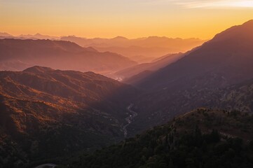 Obraz premium Sunset casting a hazy glow over highways winding through mountainous terrain