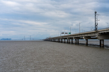 Obraz premium long bridge on mudflat beach and sea on a cloudy day