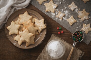 Assorted star-shaped cookies on a rustic ceramic plate and baking tray, vibrant sweets in a circular jar, powdered sugar in a glass container with a wooden spoon on a wooden surface