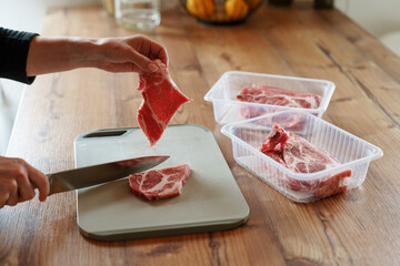 Cutting raw pork meat in kitchen