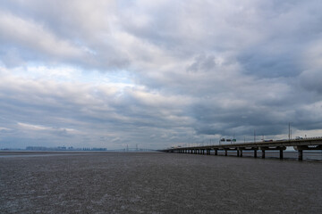 Obraz premium long bridge on mudflat beach and sea on a cloudy day