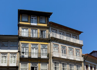 Elegant historic houses in the center of Guimaraes, Portugal, featuring large white-framed windows,