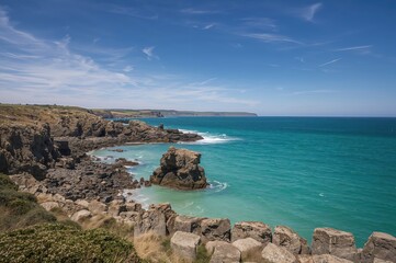 Upright perspective of towering stone structures above a vibrant blue ocean