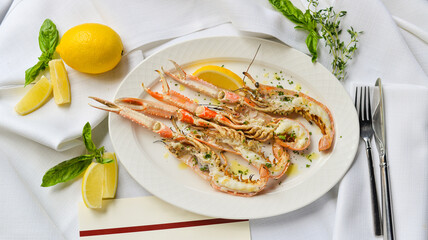 three halved scampi in a plate with lemon and lime on the table
