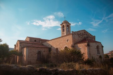 Obraz premium Ancient stone chapel under a clear summer sky, perfect for travel and exploration, showcasing classic architecture on a serene island.