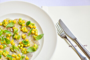 fish carpaccio decorated with corn and basil macro photo